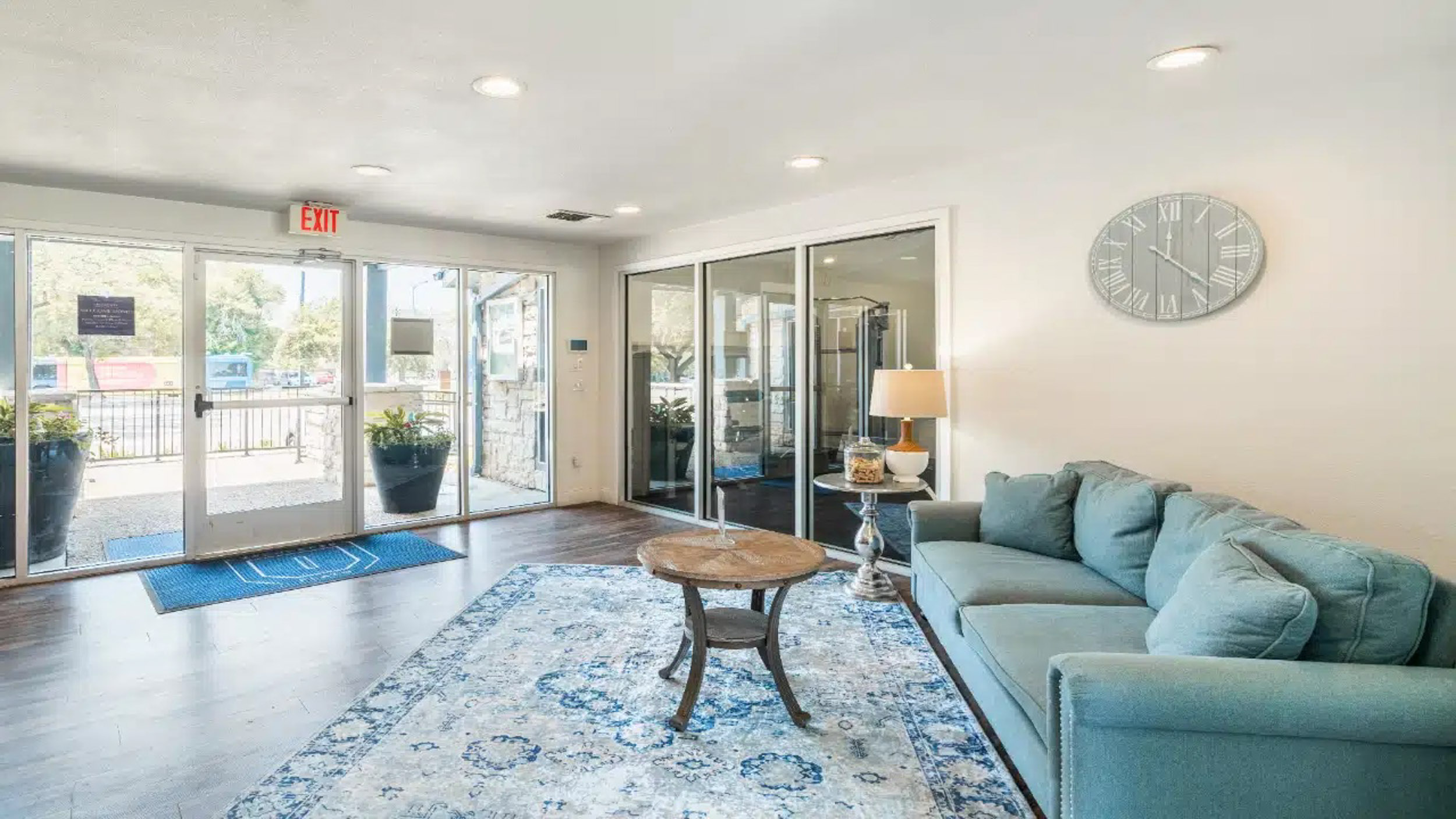 Sofa in resident clubhouse with fitness center in background