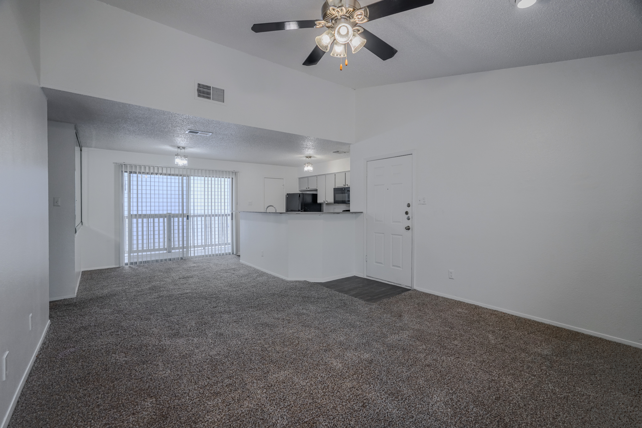 a living room with a ceiling fan and a counter