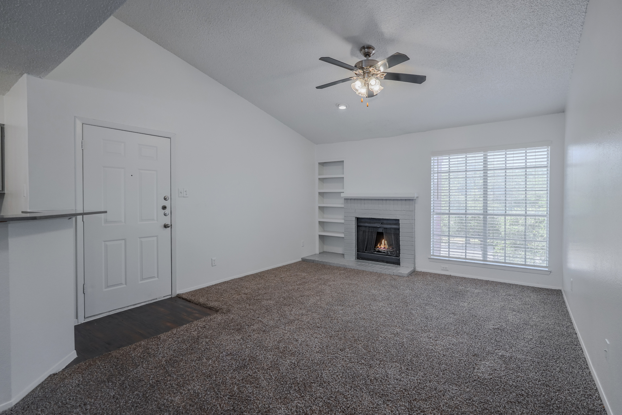 a living room with a fireplace and a ceiling fan